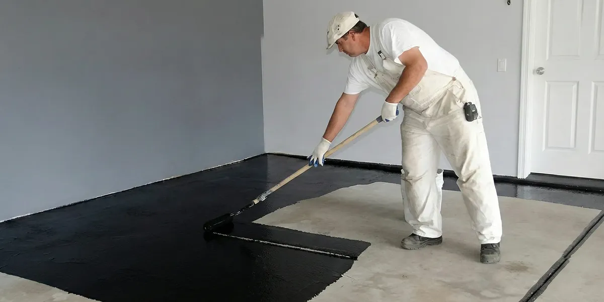 basement waterproofing professional applying waterproof coating to protect a basement floor in San Antonio, TX